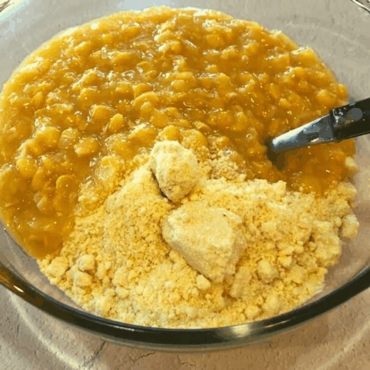 Mixing Jiffy Cornbread Mix with corn in a medium-sized bowl.