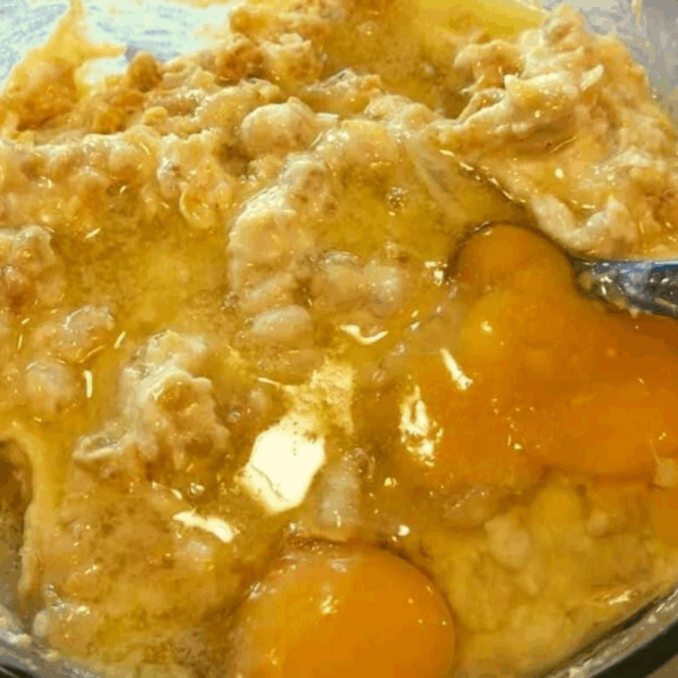 Mixing eggs, sugar, and melted butter into the cornbread batter.