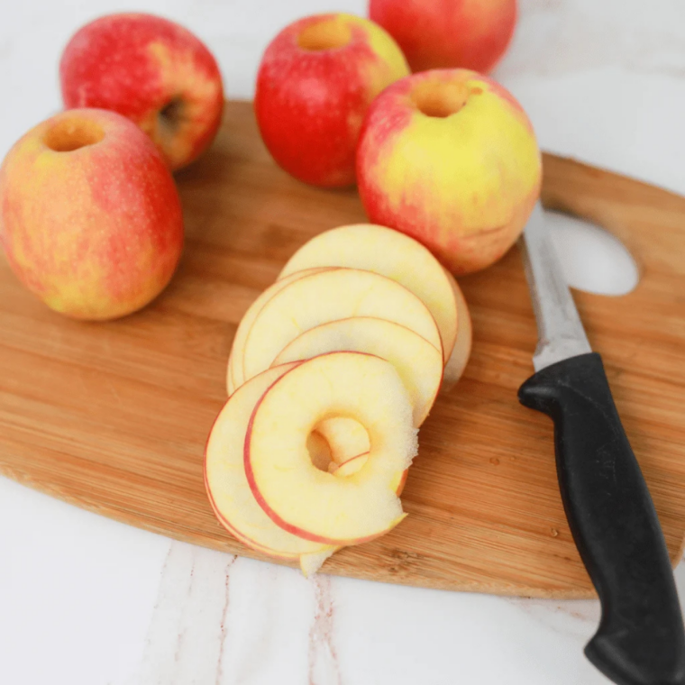 Washed apples being cored and sliced into thin ⅛-inch rounds using a mandoline slicer for air fryer apple chips.