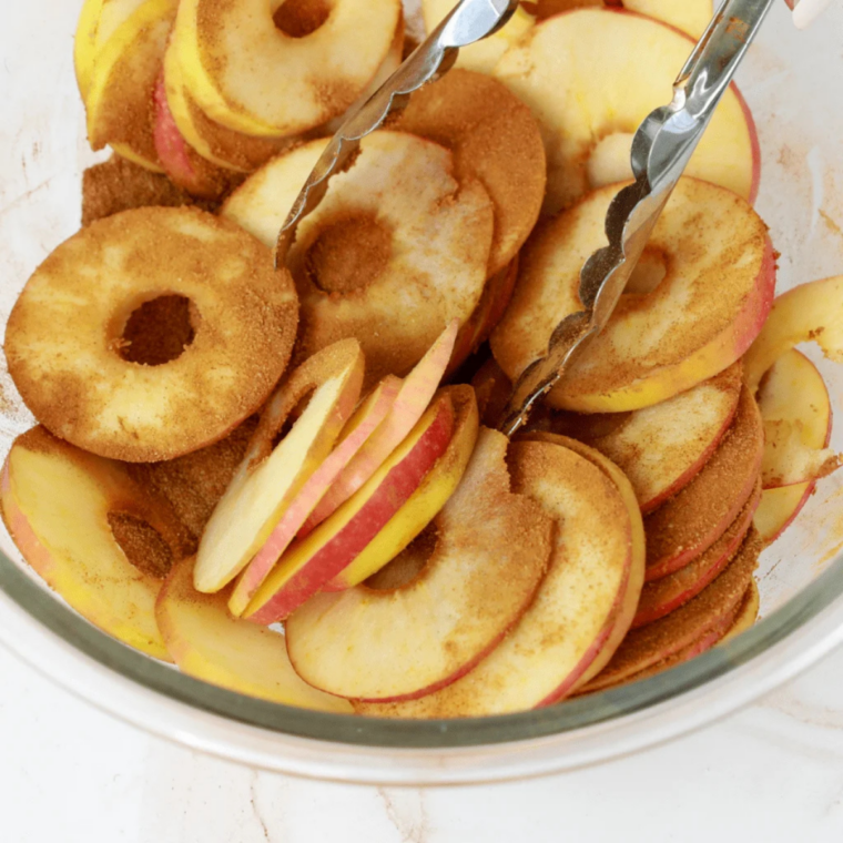 Apple slices soaking in lemon water to prevent browning before air fryer dehydration.