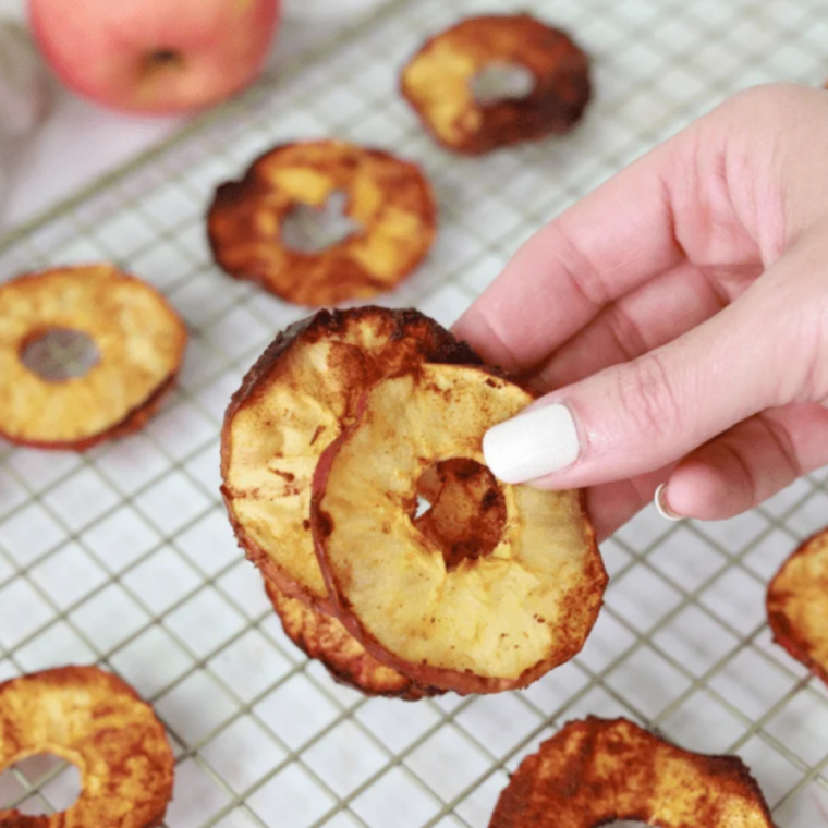 Thin apple slices coated with cinnamon in an air fryer basket