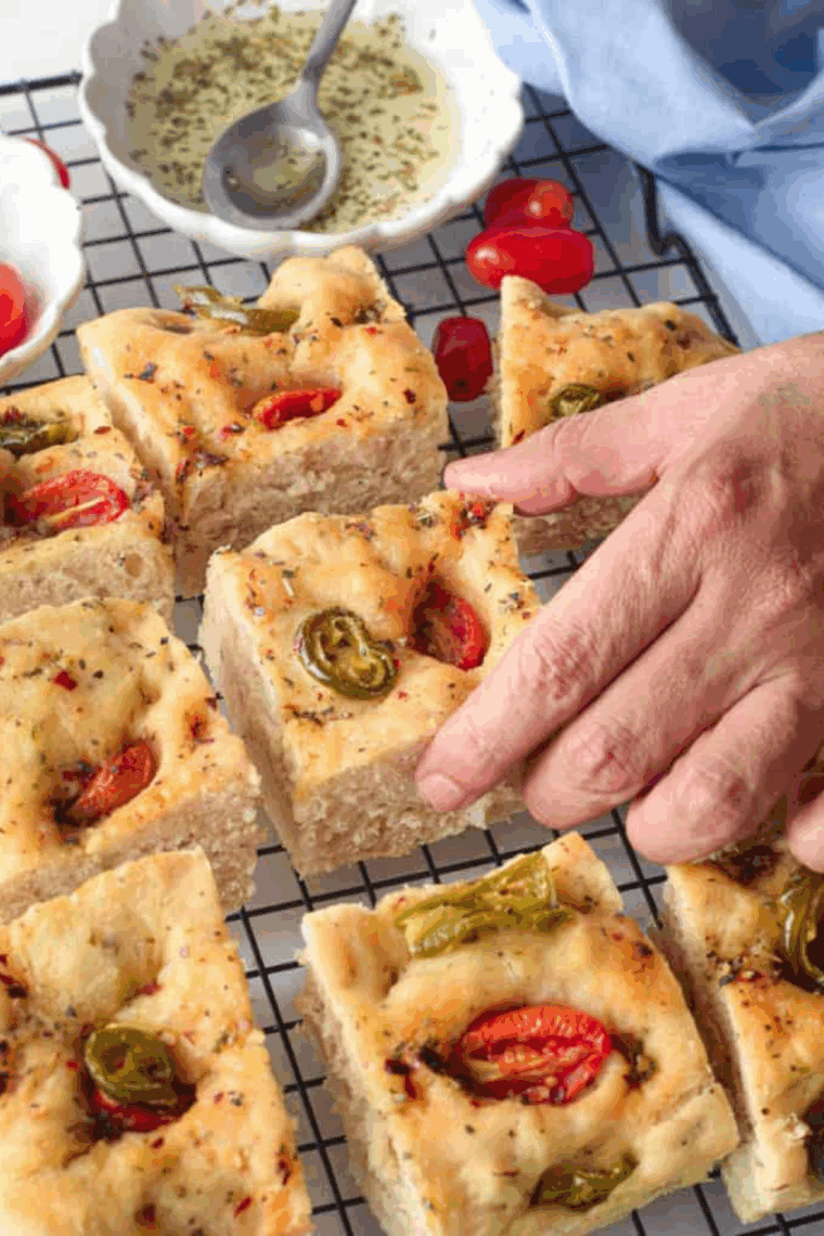 Golden focaccia bread made in the Instant Pot, topped with herbs and vegetable.