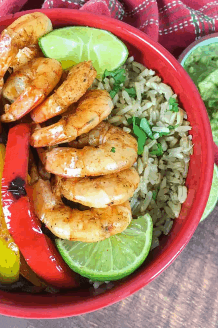 Air fryer shrimp fajita bowl with seasoned shrimp, peppers, onions, and rice, topped with fresh herbs and garnishes.
