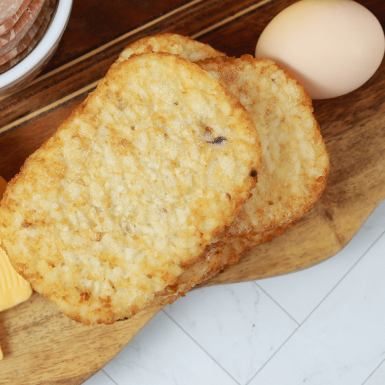 overhead closeup: air fryer trader joe's hashbrowns on a wooden cutting board with an egg
