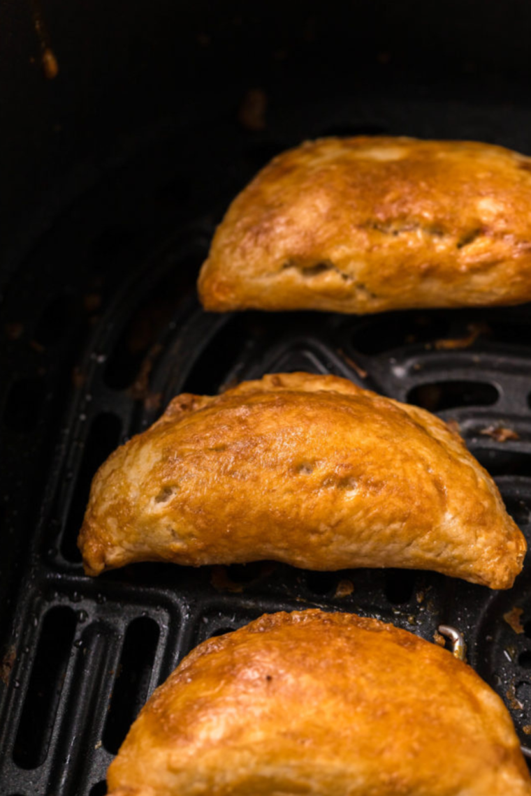 Air Fryer basket filled with freshly cooked Breakfast Empanadas, golden and crispy.