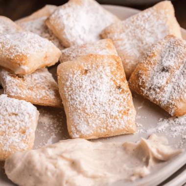 Copycat Marco's CinnaSquares piled on a white plate with vanilla icing for dipp