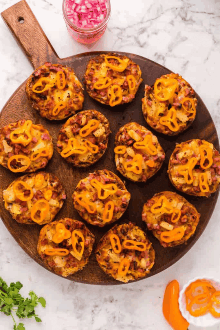 Gluten free pizza bagels in air fryer topped with melted cheese, pepperoni, and colorful vegetables.