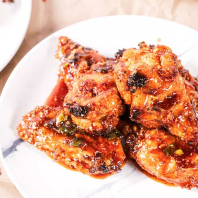 Air Fryer Korean Chicken Wings coated in spicy glaze and garnished with sesame seeds and green onions"