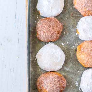 Air fryer pumpkin cheesecake donut holes rolled in cinnamon sugar stacked on a white plate