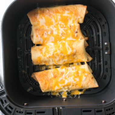 Crispy air fryer shrimp chimichangas cut open to show shrimp, rice, beans and melted cheese
