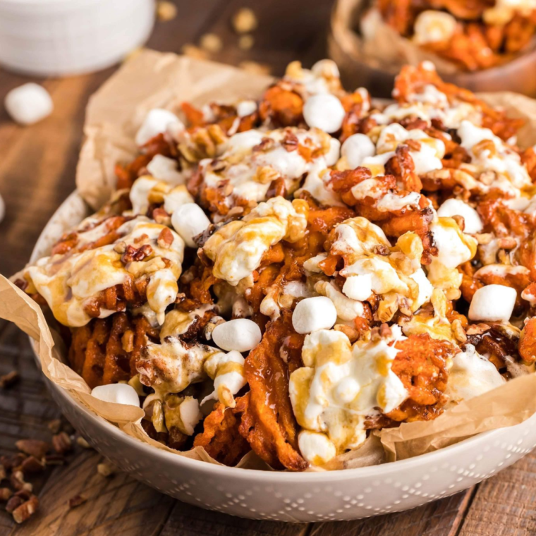 "Basket of colorful sweet potato nachos topped with cheese, jalapeños, and fresh herbs, served with dipping sauce.