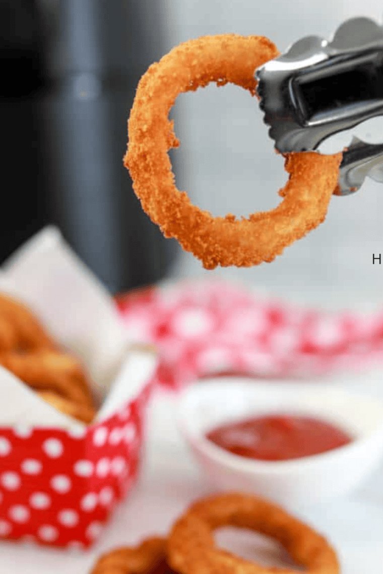 Golden and crispy Alexia Onion Rings cooked in the air fryer, served with a side of dipping sauce on a plate.