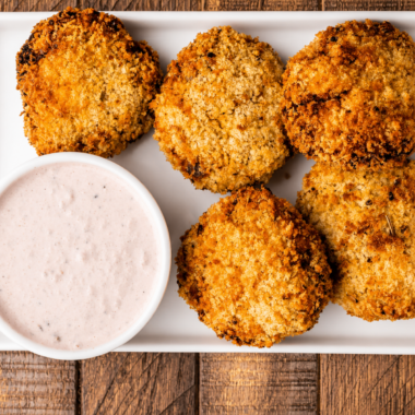 Creamy cranberry dip in a white bowl served next to golden fritters