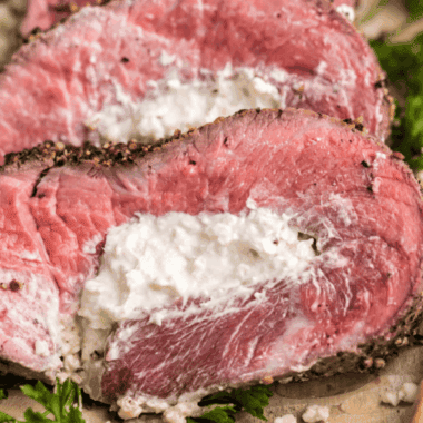 Sliced Black and Blue steak showing a dark, nearly black crust and a cool, bright red interior (blue-rare), served on a white plate.