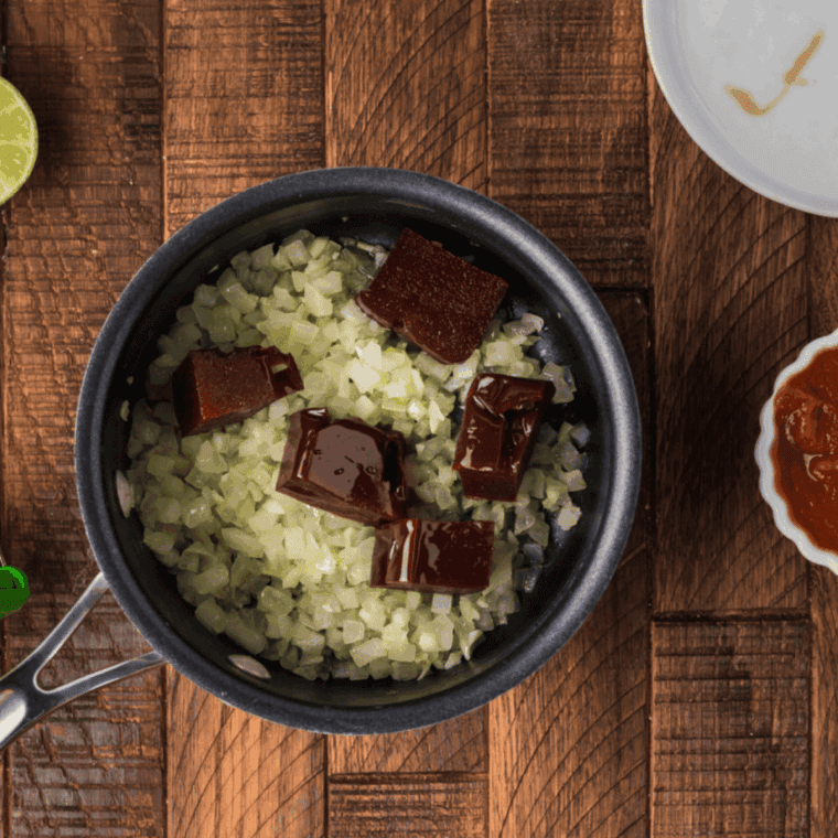 Cooking minced garlic, chopped guava, and diced onion in olive oil in a saucepan over medium heat.
