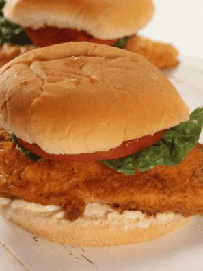 Golden fried chicken sandwich with lettuce and bun on a plate, homemade Jack in the Box style.