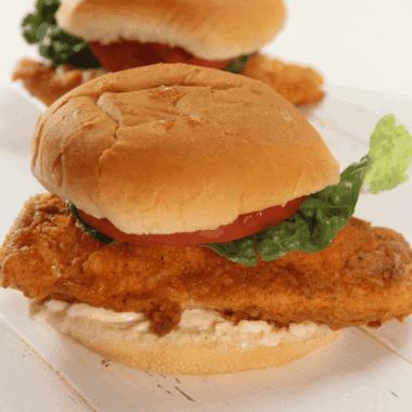 Golden fried chicken sandwich with lettuce and bun on a plate, homemade Jack in the Box style.