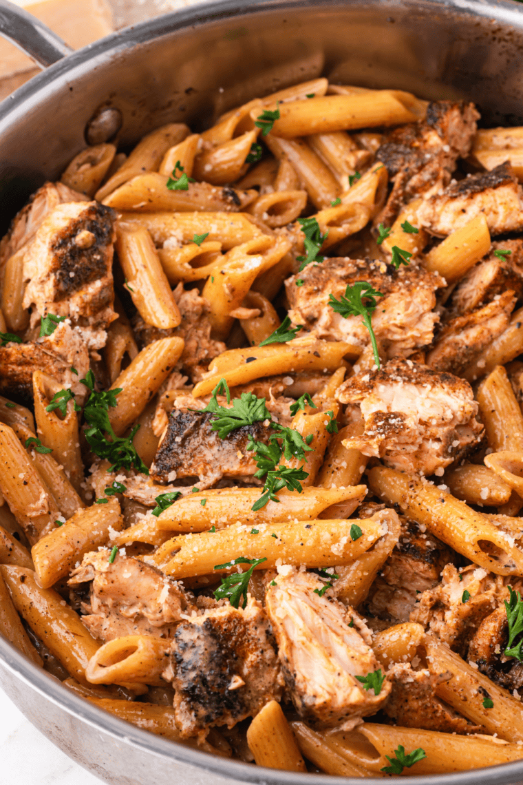 Creamy Cajun pasta in a cast iron skillet with a spiced tomato cream sauce, garnished with fresh parsley