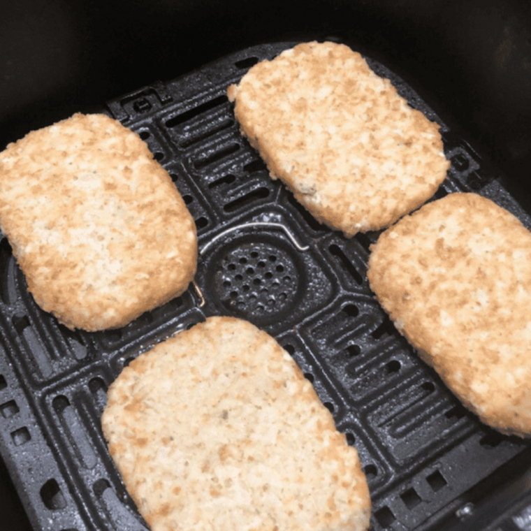 Frozen hash brown patties arranged in a single layer in the air fryer basket with space between each patty for even airflow and crisping without overlapping