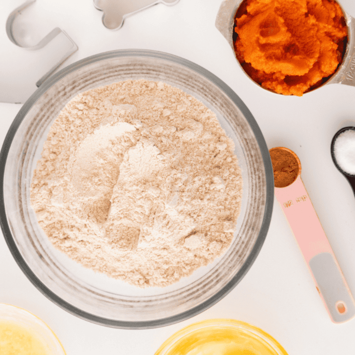 Mixing flour, eggs, pumpkin, and spices into a dough for homemade dog treats.