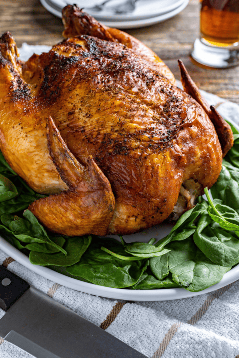 Whole seasoned beer can chicken cooked in an air fryer with golden crispy skin and juicy meat inside the basket.