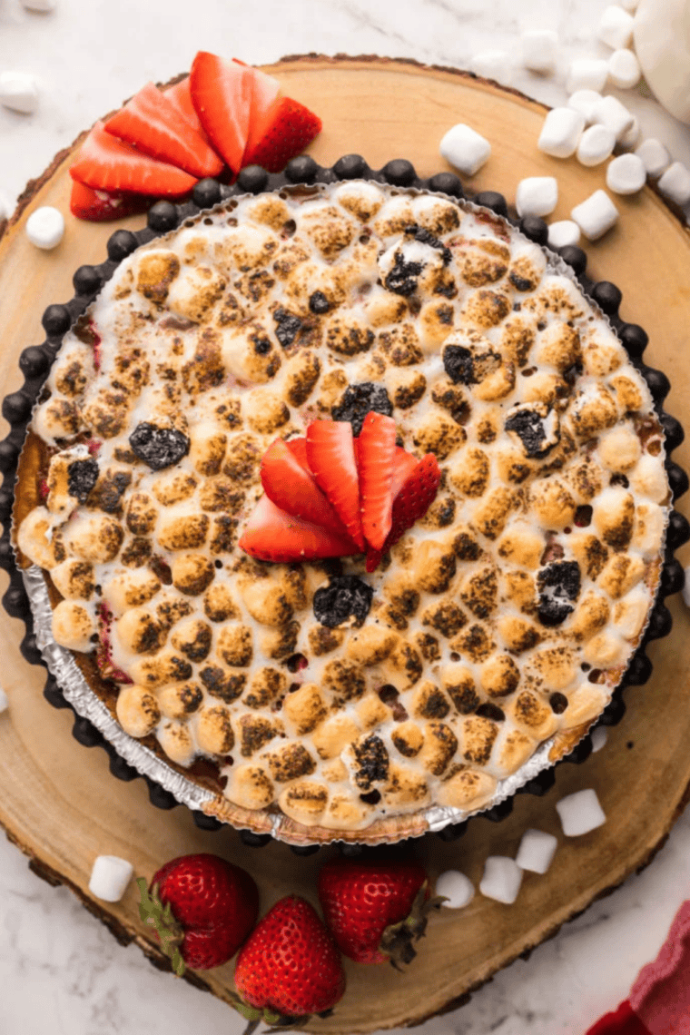Air Fryer Berry S’mores Cheesecake with graham cracker crust, fresh berries, and toasted marshmallows on top.