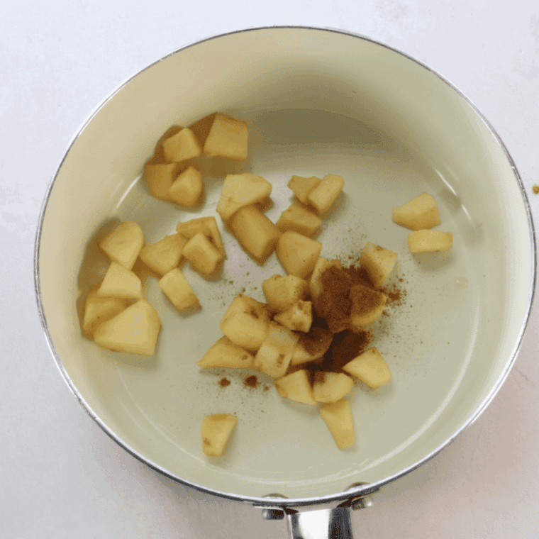 Diced apples being sautéed in a skillet with butter, caramel sauce, and apple pie spice.