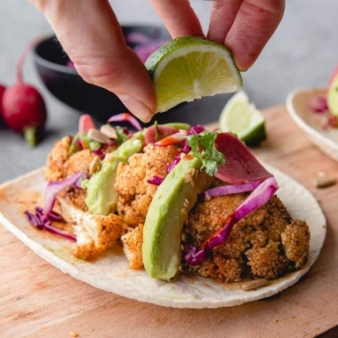 Crispy cauliflower tacos served with fresh veggies and lime on the side