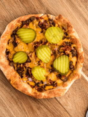 Sliced air fryer cheeseburger pizza topped with ground beef, bacon, cheddar, and dill pickles
