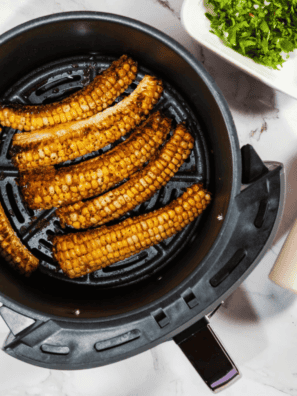 Air fryer corn ribs on a white plate topped with chipotle mayo, cotija cheese, and cilantro