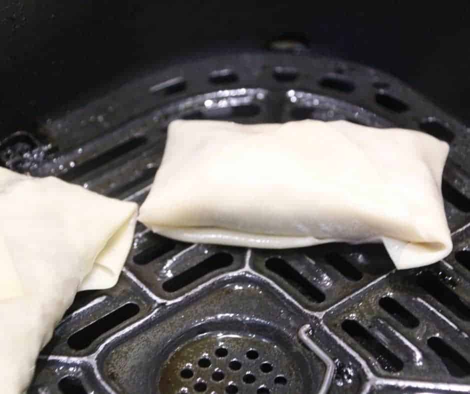 closeup: cooking air fryer egg rolls in air fryer basket