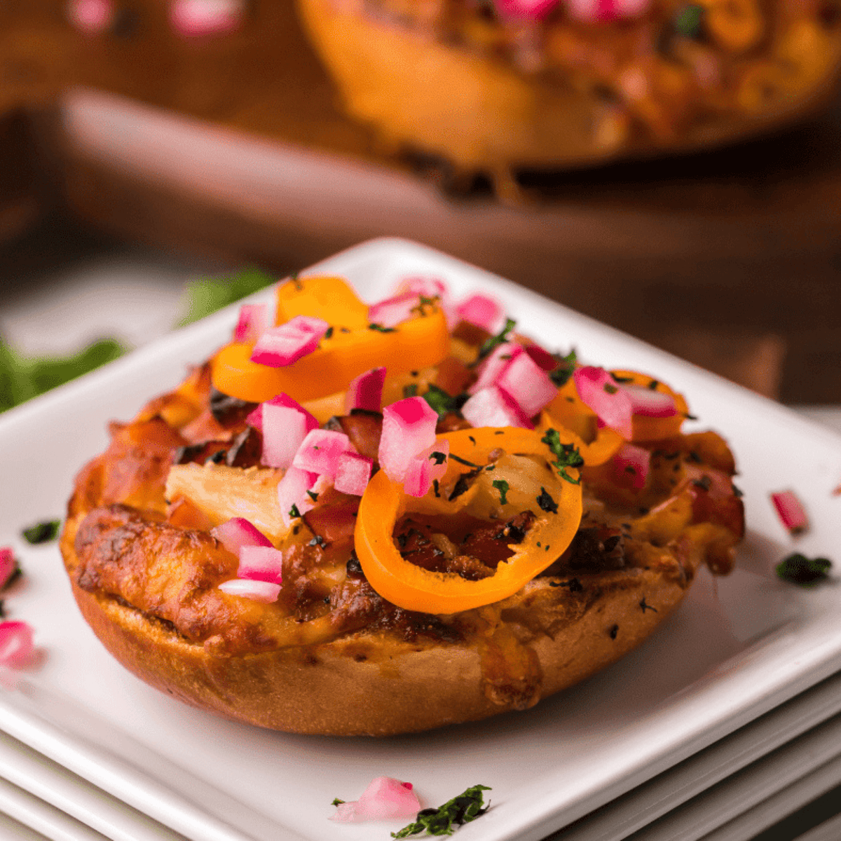 Crispy Hawaiian pizza bagel bites in air fryer, topped with melted cheese, ham, and pineapple chunks.
