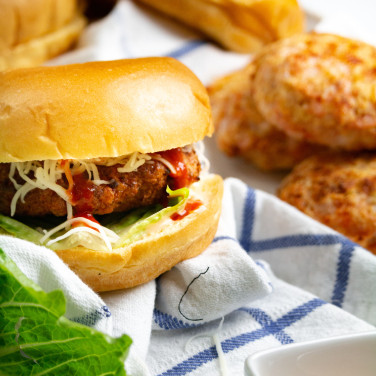 A shrimp burger being placed in an air fryer basket, ready for cooking to perfection.