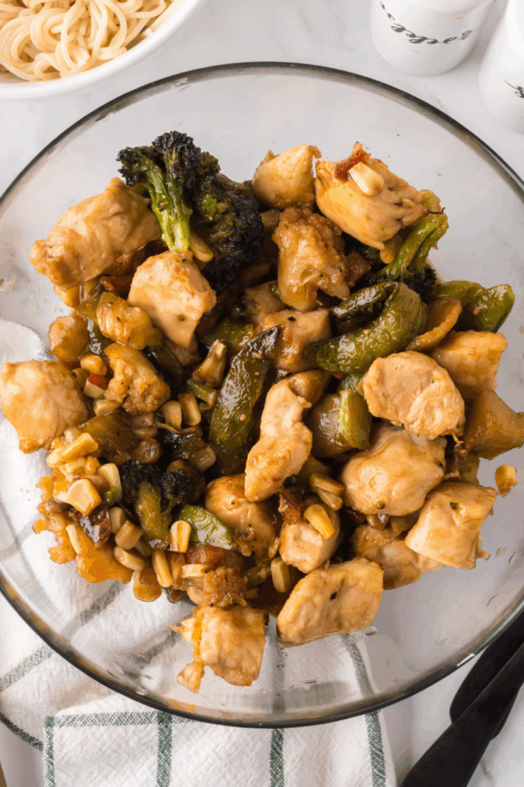 Blackstone griddle chicken stir fry with colorful bell peppers, broccoli, and carrots cooking in a savory sauce.