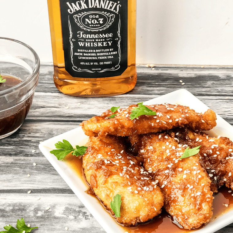 Crispy Copycat Whiskey-Glazed Sesame Chicken Strips with sesame seeds and a sweet, smoky glaze.