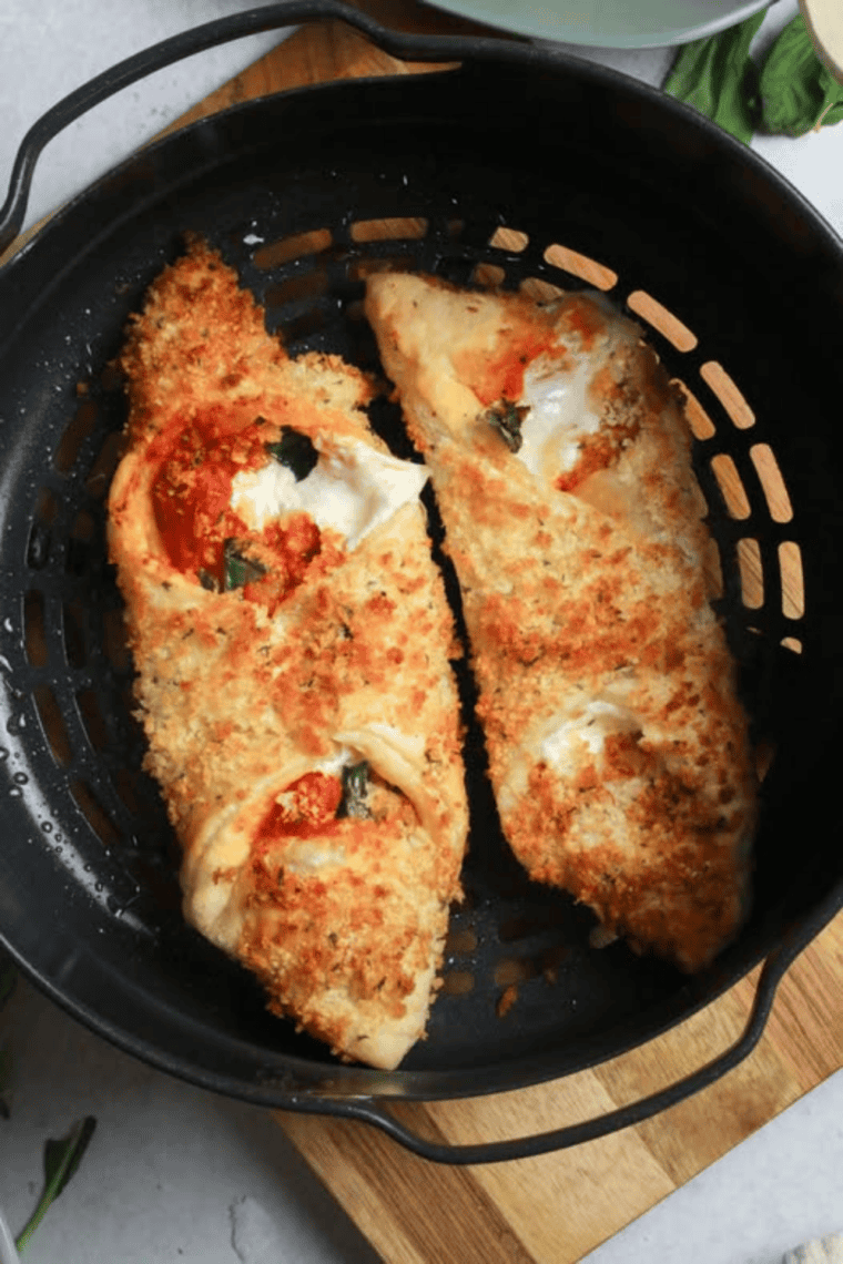 Golden Air Fryer Pizza Cannoli filled with melted mozzarella, tomato sauce, and fresh basil on a plate.
