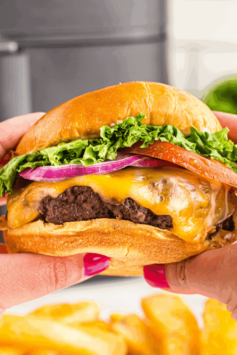 Shake Shack Burger Recipe in hands showing a juicy burger.