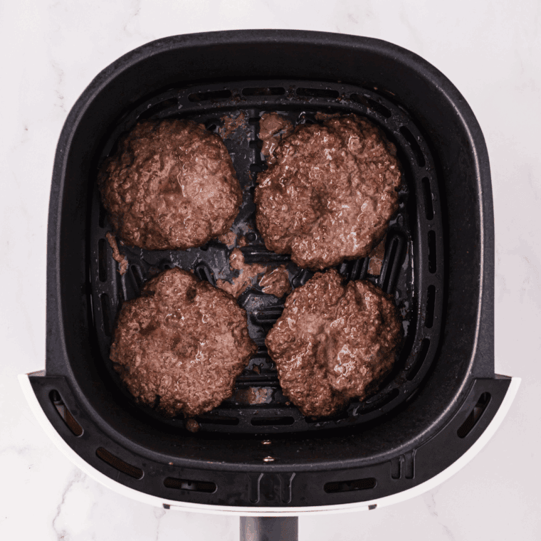 Cooked burgers in the air fryer basket.
