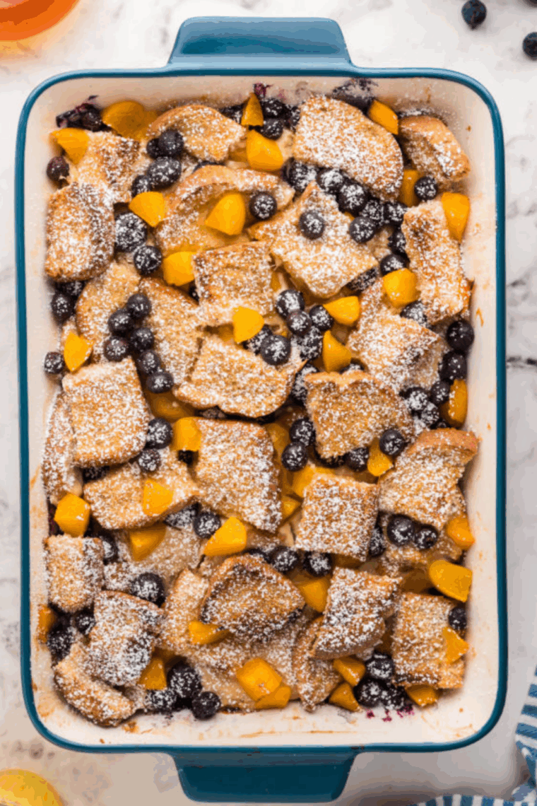 Sourdough French toast casserole baked until golden, with cinnamon swirls and a crisp, buttery top in a white baking dish.