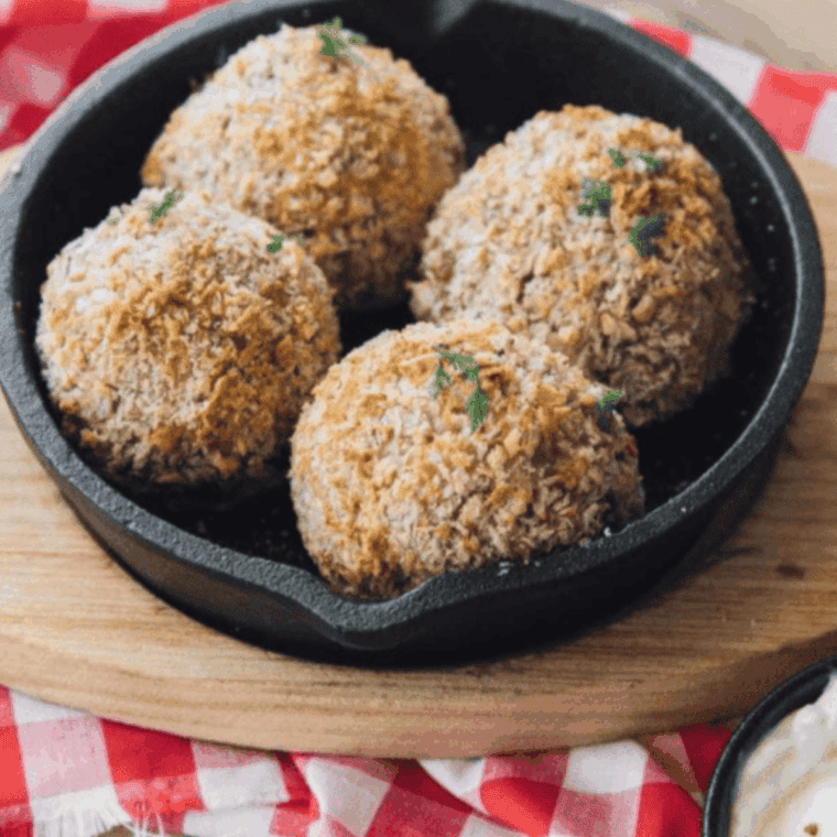 Golden air fryer arancini arranged on a plate, one split open showing a melty cheese center