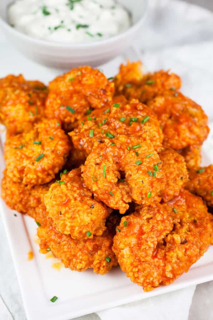What temperature should I set my air fryer to for Buffalo Shrimp? Preheat your air fryer to 370 degrees F for Buffalo shrimp for 2-3 minutes. This high heat helps achieve a crispy exterior while ensuring the shrimp cook through.

How long do I cook Buffalo shrimp in an air fryer? Cooking times can vary depending on the size of the shrimp and the specific air fryer model. As a general guideline, cook large shrimp (jumbo or extra-large) for about 8-10 minutes, flipping halfway through the cooking time. However, checking the shrimp for doneness and adjusting the cooking time accordingly is recommended. Use a meat thermometer and check the internal temperature in the thickest part of the shrimp; when the meat thermometer reads 145 degrees F, you can safely remove the shrimp from the air fryer basket. 

Can I use frozen shrimp for Buffalo shrimp in the air fryer? Yes, you can use frozen shrimp, but it's recommended to thaw them completely before cooking. Thawing the shrimp allows for even cooking and better adherence to the coating and sauce.

What type of sauce can I use for Buffalo shrimp? Traditional Buffalo sauce combines hot sauce (such as Frank's RedHot) and melted butter. However, you can customize the sauce by adding additional ingredients like garlic powder, Worcestershire sauce, or vinegar to suit your taste preferences.

How do I make the Buffalo shrimp less spicy?  If you prefer milder heat, you can adjust the spiciness of the Buffalo shrimp by using a milder hot sauce or reducing the amount of hot sauce used in the sauce mixture. You can also add a bit of honey or brown sugar to balance out the heat.

Can I use a different coating for the shrimp? Yes, you can experiment with different coatings. Besides flour or a mixture of flour and cornstarch, you can try using breadcrumbs (regular or panko), crushed cornflakes, or even a mixture of spices and crushed nuts for added texture and flavor.

Can I make Buffalo shrimp without using any flour or coating? While a coating helps create a crispy texture, you can still achieve a similar flavor by tossing the cooked shrimp in Buffalo sauce directly, without any coating. However, note that the shrimp will have a different texture than the traditional crispy Buffalo shrimp.

Can I reheat Buffalo shrimp in an air fryer? A: Yes, you can reheat Buffalo shrimp in the air fryer. Preheat the air fryer to 350°F (175°C), place the leftover shrimp in a single layer, and reheat for about 4-5 minutes until heated. Keep an eye on them to prevent overcooking.

How to serve buffalo shrimp

Appetizer: Buffalo shrimp makes a perfect appetizer. Serve them on a platter with toothpicks or skewers for easy grabbing. You can also add a side of celery sticks and carrot sticks for a classic Buffalo flavor combination.

Salad: Create a Buffalo shrimp salad by adding the cooked and sauced shrimp to a bed of mixed greens or your favorite salad base. You can include toppings like cherry tomatoes, sliced cucumbers, crumbled blue cheese, sliced green onions, and a drizzle of ranch or blue cheese dressing.

Sandwich/Wrap: Transform your Buffalo shrimp into a delicious sandwich or wrap. Use a soft roll, baguette, or corn tortilla, and layer the shrimp with lettuce, tomato, sliced onion, and a dollop of ranch or blue cheese dressing. It makes for a flavorful handheld meal. 

Tacos: Make Buffalo shrimp tacos by placing a few shrimp in a warmed tortilla. Top them with shredded cabbage or lettuce, diced tomatoes, chopped cilantro, and a drizzle of ranch or a squeeze of lime juice. Serve with a side of salsa or guacamole./

Rice or Pasta: Serve Buffalo shrimp over cooked rice or pasta for a heartier meal. Toss the shrimp with the sauce and serve it on a bed of fluffy rice or mix it into your favorite pasta dish. Add vegetables like bell peppers or peas for extra color and texture.

Sliders: Mini Buffalo shrimp sliders are perfect for parties or gatherings. Place a few sauced shrimp on small slider buns or dinner rolls. Add some lettuce, tomato, and a touch of ranch or blue cheese dressing. Skewer them with toothpicks for easy handling.