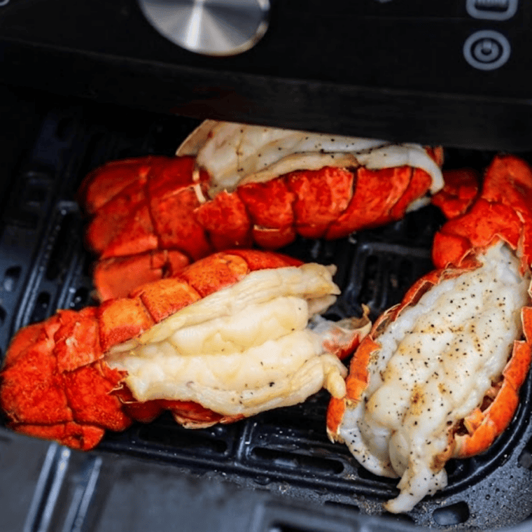 Finished air fryer lobster tails garnished with parsley and served with lemon wedges