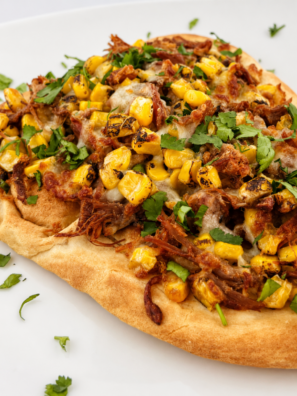 Slice of air fryer street corn carnitas flatbread topped with avocado and cotija