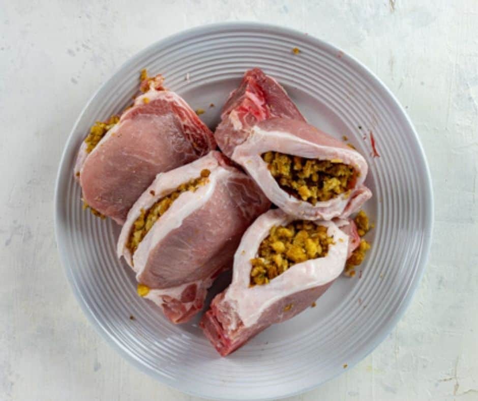 overhead: a plate of uncooked air fryer stuffed pork chops with stuffing visible
