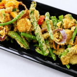 Plate of air fryer vegetable tempura with golden panko-crusted zucchini, sweet potato, and green beans beside a bowl of tentsuyu dipping sauce