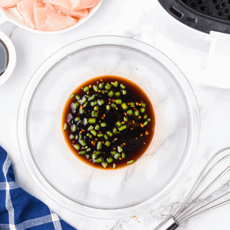 Mixing soy sauce, brown sugar, mirin, garlic, and ginger in a bowl to make teriyaki sauce.