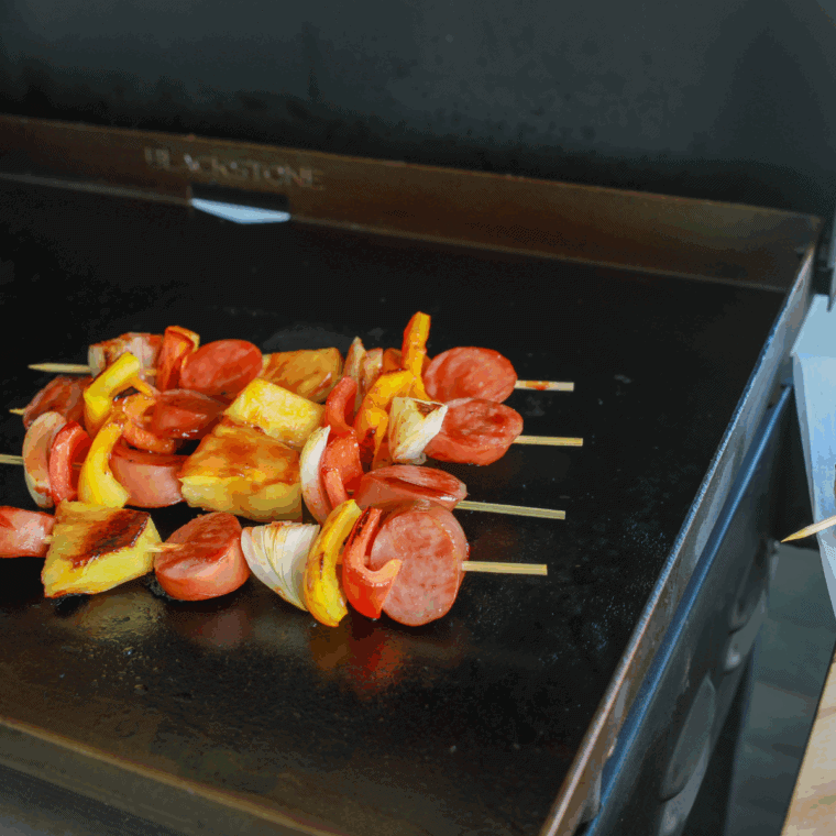 Juicy kielbasa slices sizzling on a hot Blackstone griddle.