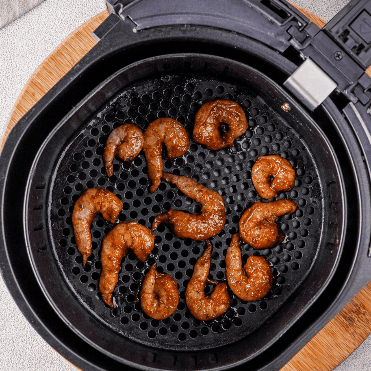 Seasoned shrimp arranged in a single layer in an air fryer basket, cooking for 6–8 minutes with a shake halfway for even crispiness.