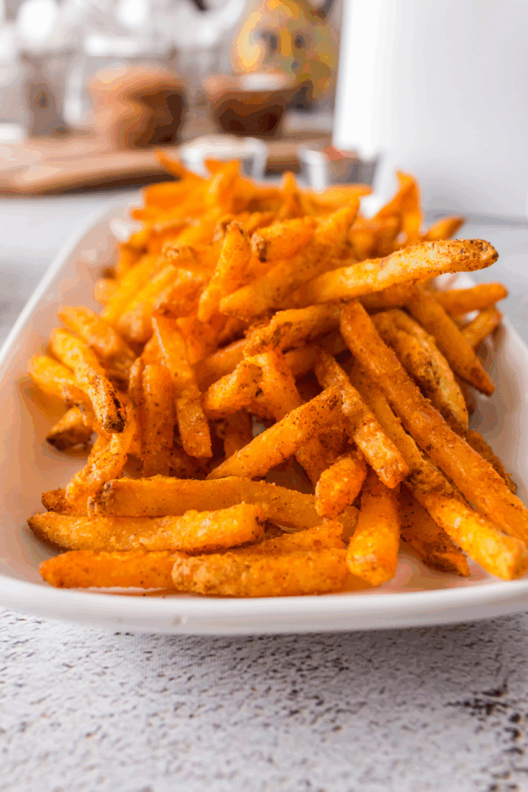 Basket of crispy, golden seasoned fries sprinkled with herbs and spices, served with ketchup.
