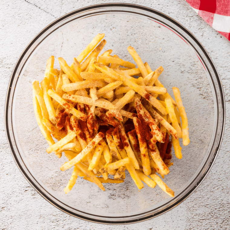 Mix the frozen French fries in a large mixing bowl, adding in the spices.